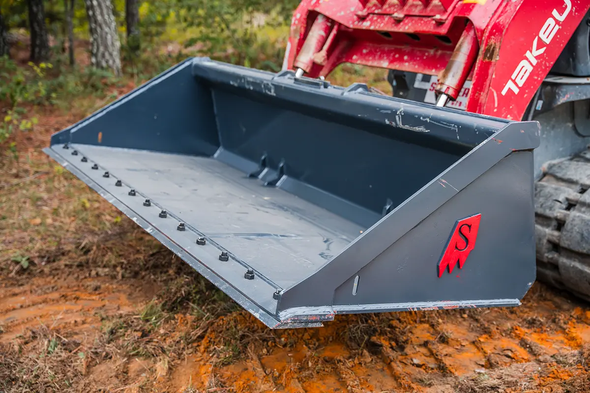 Skid Steer Bolt On Edge Bucket on Takeuchi TL10V2 in Dirt in Woods 2- Solesbee's Equipment